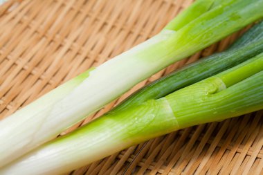 Hasır sepetin arka planında taze yeşil soğan 