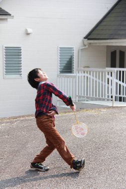Japon çocuk arka bahçede badminton oynuyor.