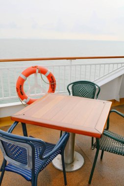 Okyanusun kenarındaki ahşap masayı çevreleyen boş sandalyeler.