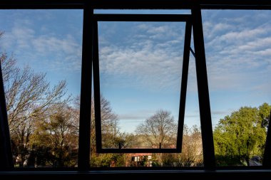 Ağaçları ve bulutlu gökyüzünü gösteren pencere görünümünü aç