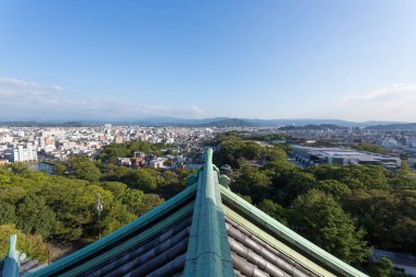 Yeşil ağaçlar arasında geleneksel çatıdan manzaraya bakan