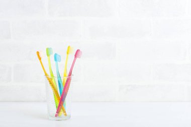 glass of colorful tooth brashes on white 