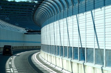 Modern mimari yapı ve camlarla çevrili kıvrımlı bir yol.