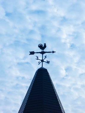 Kilise kulesinin tepesindeki rüzgar gülü Bulutlu mavi gökyüzüne karşı