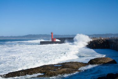 Büyük deniz dalgaları kayalık plajı eziyor.