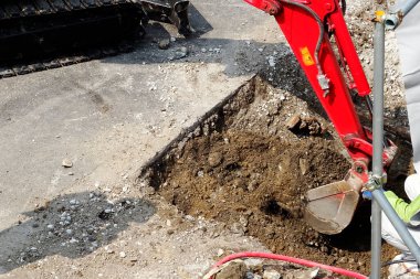 Güneşli gündüz inşaatında asfalt yol kazan kırmızı kazıcı