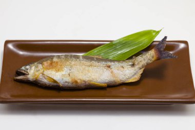 Tabağında yeşil yaprak olan lezzetli ızgara balığın yakın plan görüntüsü     