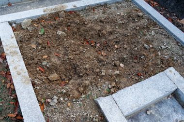 Taze kazılmış toprak dikdörtgen taş sınırın içinde sonbahar yaprakları.