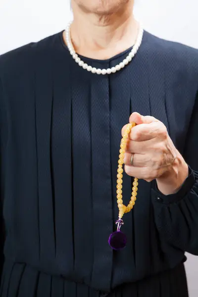 Woman in a mourning dress with prayer beads