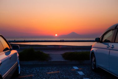 Park etmiş arabalarla denizin üzerinde güzel bir gün batımı