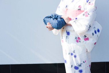 Mavi Furoshiki 'ye sarılı bento tutan kimono giyen genç bir kadın.