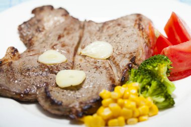 Beyaz tabakta nefis ızgara biftek ve sebze manzarası.                  
