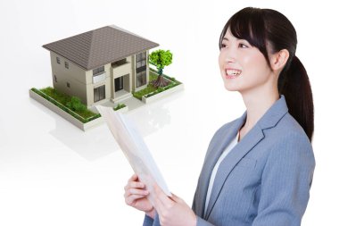 Arka planda belge ve ev modeli tutan genç bir kadın. 