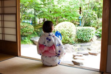 Kimono giyen Japon kadın Anthwa 'da oturuyor ve bahçeye bakıyor.