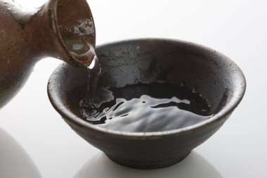 Japon sake 'sini şişeden killi fincana dök