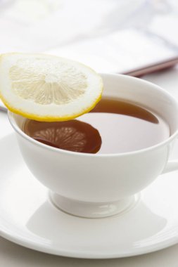 Bir bardak limon dilimli çay ve akıllı telefon.
