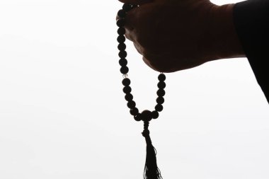 Beyaz arka planda tespihi tutan el.