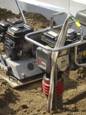 Titreşimli plaka sıkıştırıcı dışarıda gevşek inşaat toprağında dinleniyor.