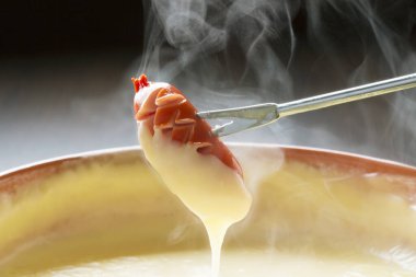 Erimiş peynir, peynir fondüsündeki bir parça taze ekmekten yayılan iplerle damlıyor..