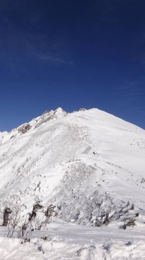 Bulutlu gökyüzünün altındaki karlı dağ, gündüz görüşü 