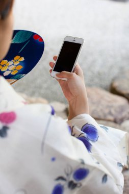 Kimono giyen genç Japon kadın akıllı telefon kullanıyor. 