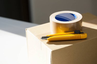 İskoç bandı ve karton kutuda kırtasiye bıçağı.