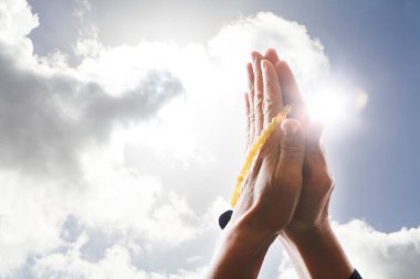 Elleri ve avuçlarıyla dua eden kadın tespih, inanç, maneviyat ve din kavramını bir arada tutuyor.