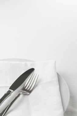 Çatallı, bıçaklı ve peçeteli beyaz tabak.