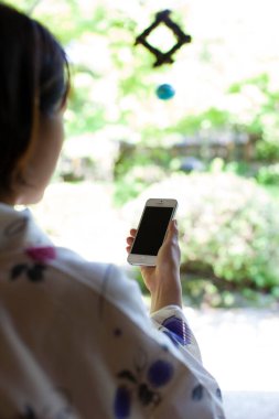 Kimono giyen genç Japon kadın akıllı telefon kullanıyor. 