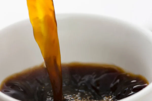 close up of coffee is pouring into white cup