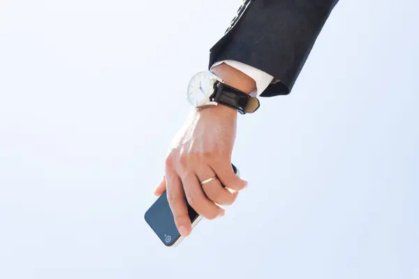 青空の上にスマートフォンを握るビジネスマンの手 — ストック写真