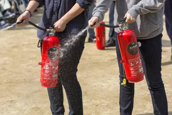 Arka planda yangın söndürücüleri olan insanlar.
