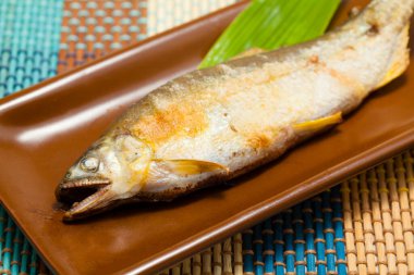 Tabağında yeşil yaprak olan lezzetli ızgara balığın yakın plan görüntüsü     