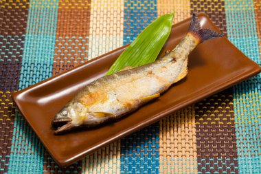 Tabağında yeşil yaprak olan lezzetli ızgara balığın yakın plan görüntüsü     