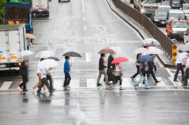 Şehir caddesinde yağmurda yürüyen şemsiyeli insanların bulanık görüntüsü                   