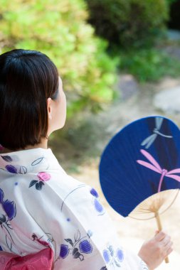 Kimono giyen Japon kadın Anthwa 'da oturuyor ve bahçeye bakıyor.