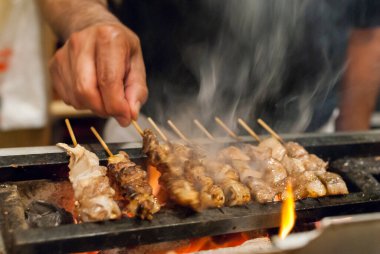 Şişler ve sokak yemekleri üzerinde et ızgara yapan kişinin yakın plan görüntüsü.