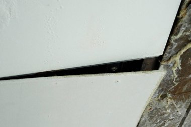 Yakın plan, sert köşenin kenarındaki çatlak beyaz duvarı gösteriyor.