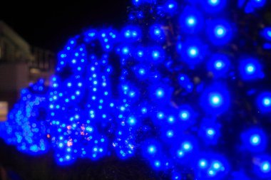 Bulanık arka plan, parlak ışıklar ve gece şehrinde noel süslemeleri.    