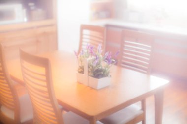 Güneş ışığı ahşap yemek masasında mor çiçeklerle parıldıyor.