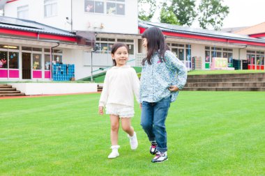 Dışarıda el ele tutuşan iki Asyalı kızın portresi.