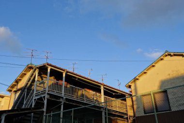 Açık mavi gökyüzü altında görünen elektrik hatları olan binalar