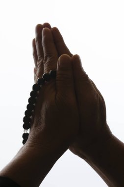 Beyaz arka planda tespihi tutan eller