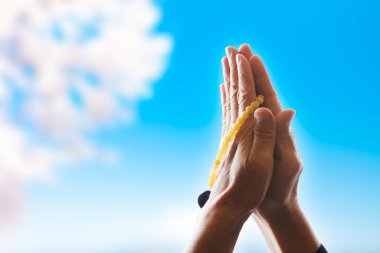 Elleri ve avuçlarıyla dua eden kadın tespih, inanç, maneviyat ve din kavramını bir arada tutuyor.