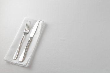 Çatal, bıçak ve beyaz arka planda beyaz bir peçete..