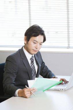 Asyalı iş adamı iş yerinde dizüstü bilgisayar kullanıyor