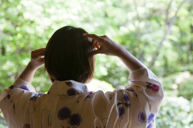 Yaz bahçesinde Japon kimonosu giyen bir kadın.