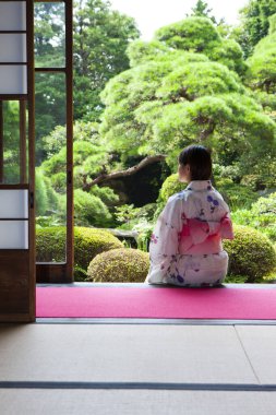 Japonların kimono giymiş arka planda oturan ve bahçeye bakan kadınlar.