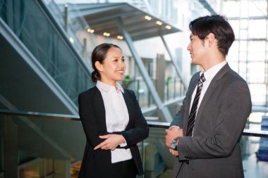 Modern ofis binasında iş adamları sohbet ediyor.