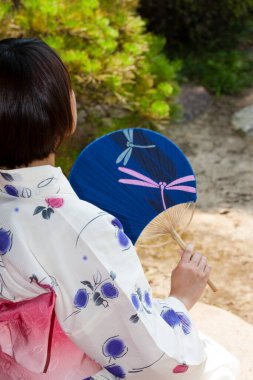 Kimono giyen Japon kadın Anthwa 'da oturuyor ve bahçeye bakıyor.